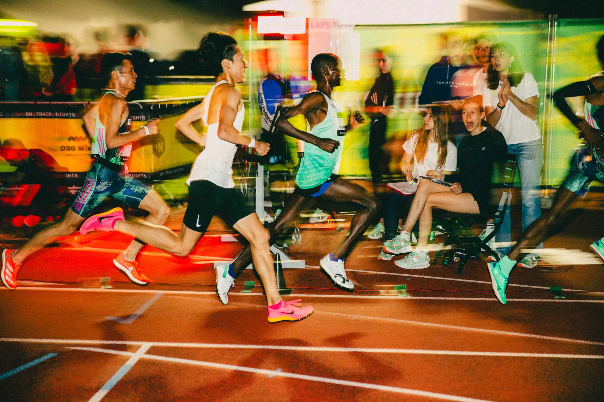 Spectators lining an outdoor track at night.